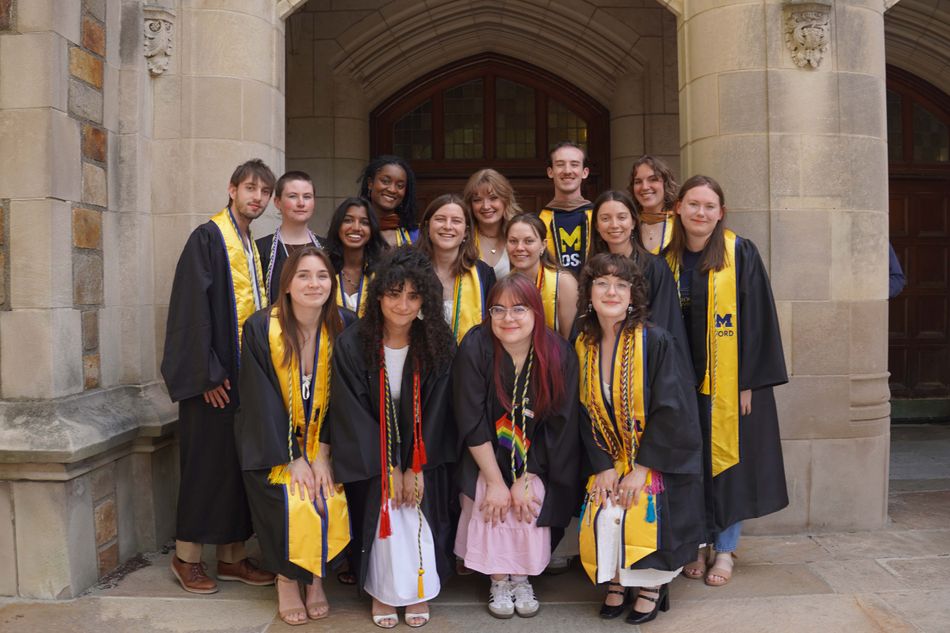 group of students in cap and gown posing for a photo and wearing the excellence in sustainability honors cord
