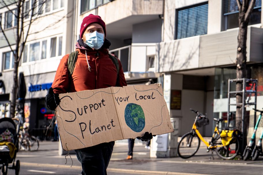 person holding a sign that says support your local planet