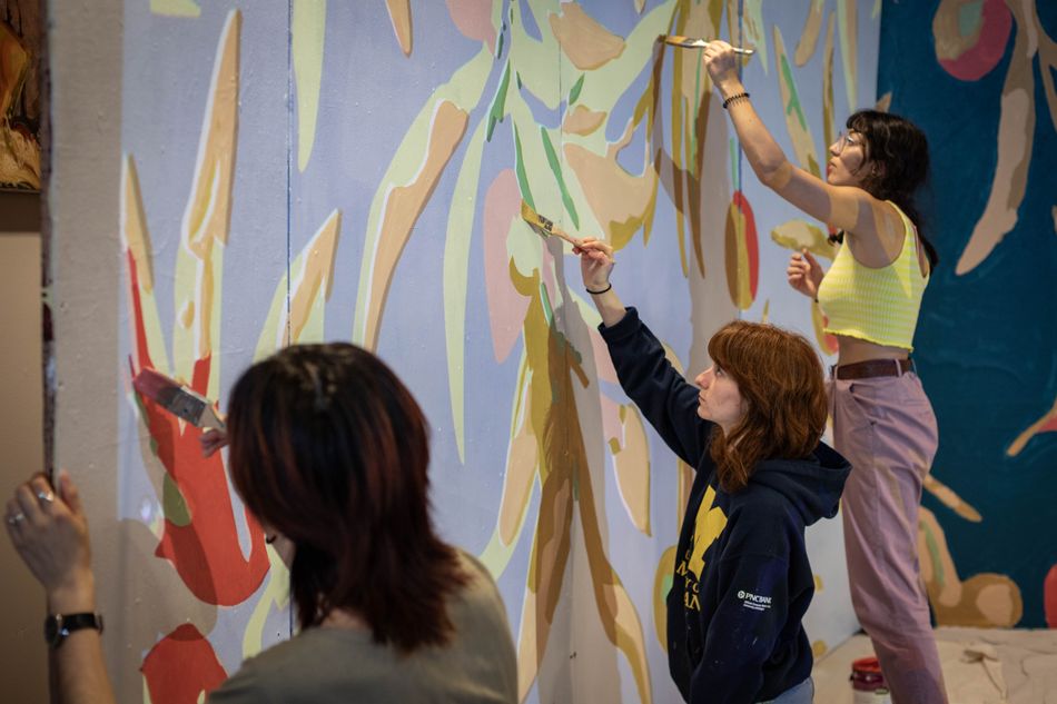 Students paint a mural on a wall 