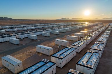 The sun shines on dozens of shipping-container sized battery energy storage systems sitting in rows in the California desert.