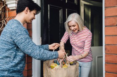 a man handing a woman a bag of groceries