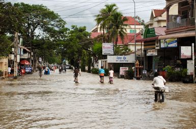 several people walking or bicycling through a flood