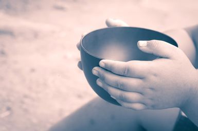A child's hands holding an empty bowl