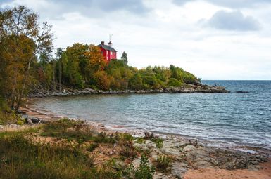 a lighthouse and lake shore; Photo by Gary Meulemans on Unsplash
