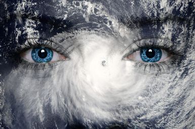 Image of a woman's eyes over a photo of a hurricane