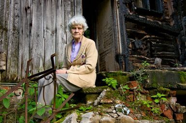 Elderly woman sitting outside a ruined building