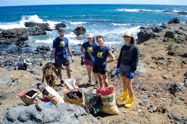 SEAS master's students (from left) Jack Baylis, Emma Fagan, and Satara Fountain, pictured with Sonja Angst (far right), a staff member at Sustainable Moloka‘i, cleaning up the coastline of Mo‘omomi Beach in Moloka‘i. Photo credit: Sierra Mathias.