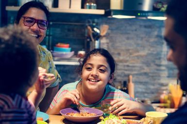 a family eating a meal together, smiling