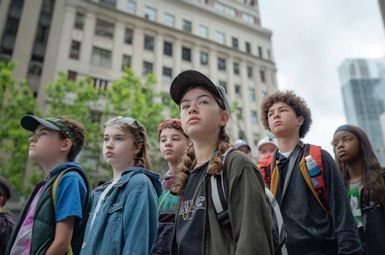 children looking in one direction in a cityscape