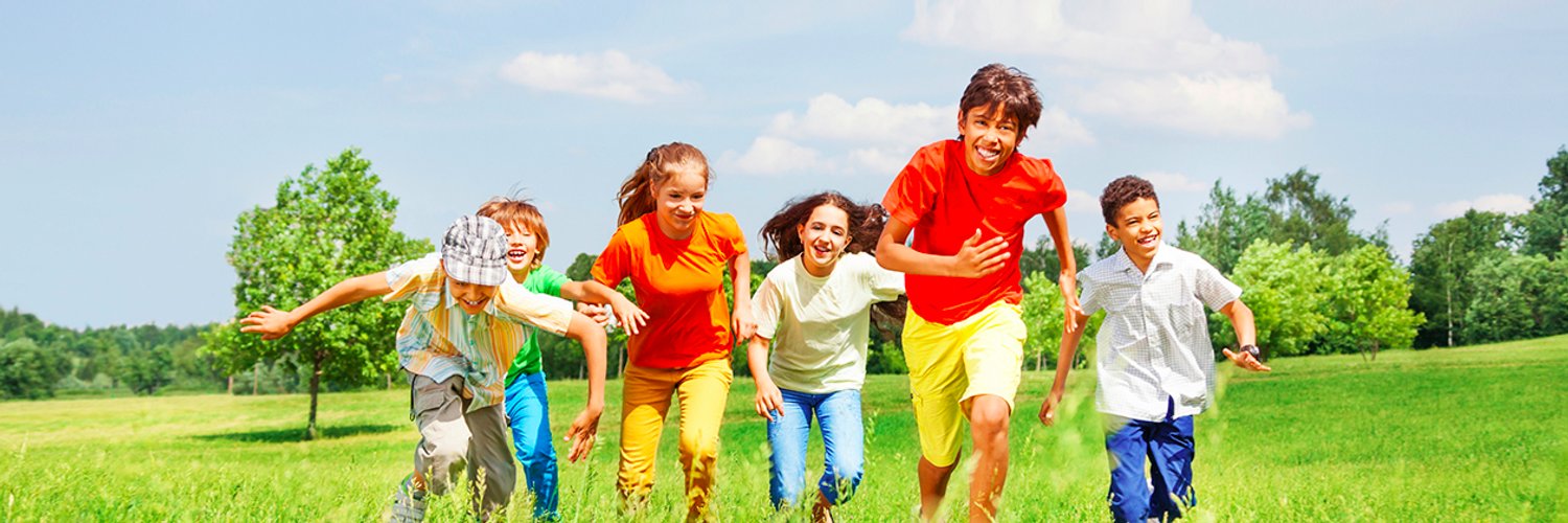 Children in bright clothing running through a field on a summer day