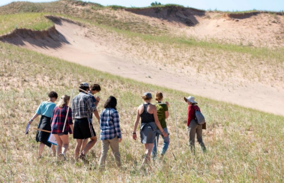A group of students gathered along sand dunes