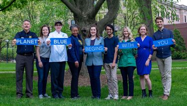 Staff holding signs that say “Planet Blue begins with you”